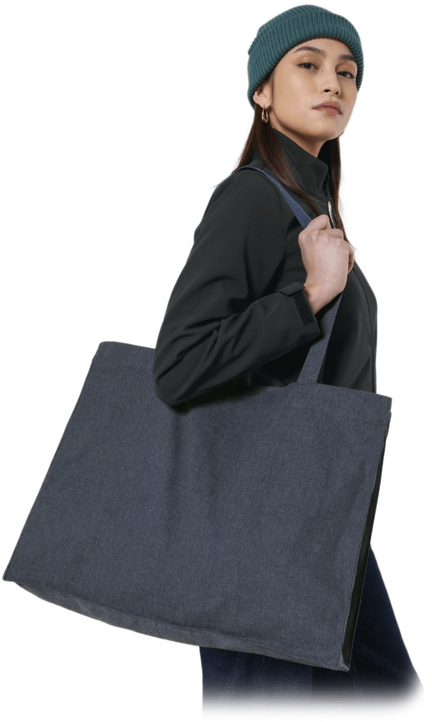 Frau mit grüner Mütze und schwarzer Jacke trägt große dunkelblaue Stofftasche über der Schulter.